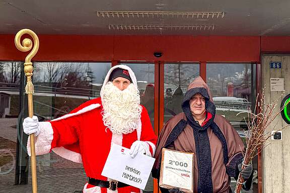 Samichlaus (Nikolaus) und Schmutzli vor dem MitMänsch»-Gebäude in Brig-Glis (VS) mit einem Brief an die Direktion und dem Unia-Appell für ein tragfähiges und menschliches Arbeitsumfeld bei MitMänsch mit 2000 Unterschriften.