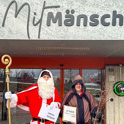 Samichlaus (Nikolaus) und Schmutzli vor dem MitMänsch»-Gebäude in Brig-Glis (VS) mit einem Brief an die Direktion und dem Unia-Appell für ein tragfähiges und menschliches Arbeitsumfeld bei MitMänsch mit 2000 Unterschriften.