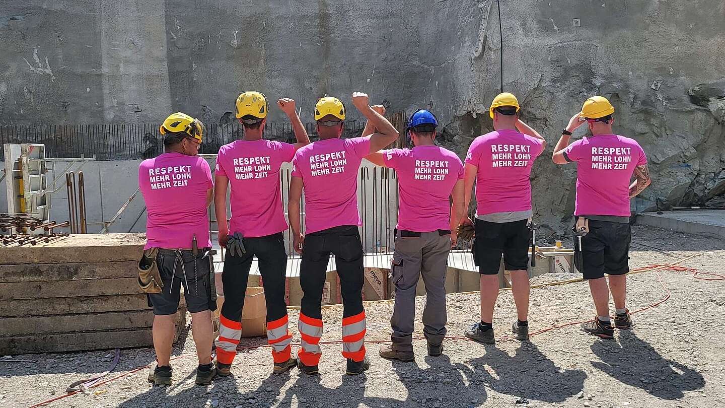  Eine Gruppe Bauarbeiter trägt Unia-Frauenstreik-T-Shirts mit der Aufschrift «Respekt, mehr Lohn, mehr Zeit» und zeigt geschlossen Haltung auf einer Baustelle.